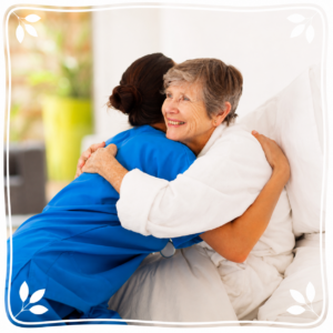 A caregiver embracing an older woman resting in bed
